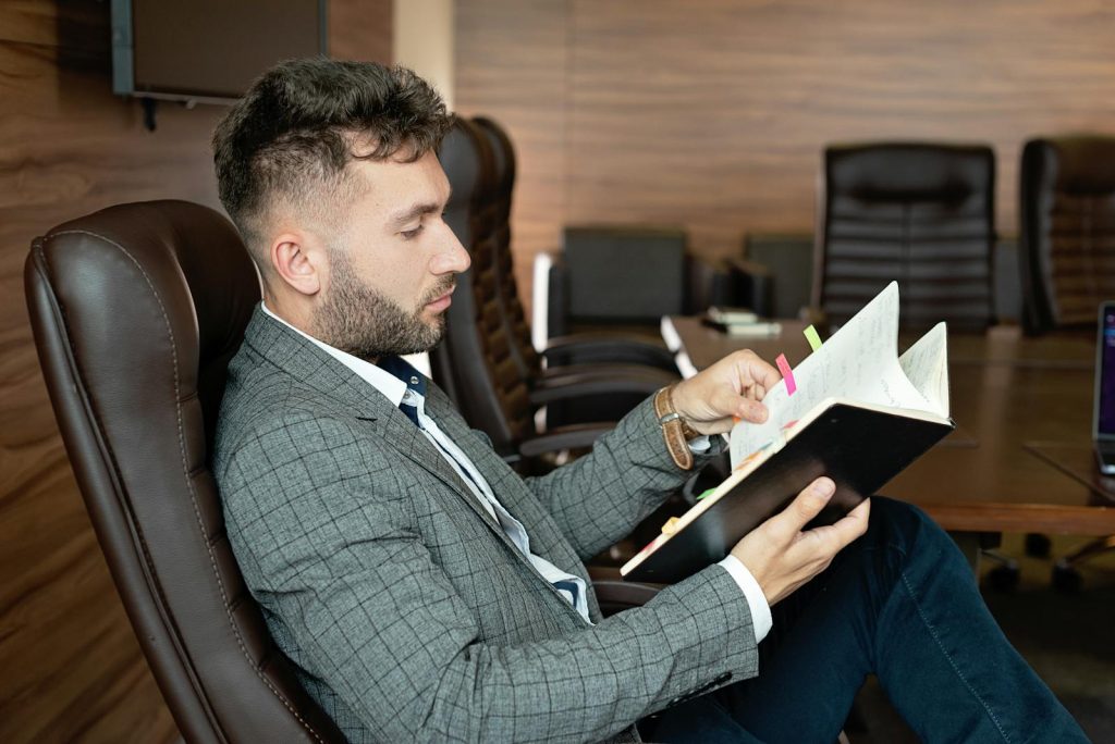 Man Sitting on the Office Chair while Holding a Book